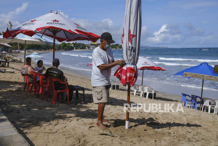 Seorang pria memasang payung di sebuah pantai di Kuta, Bali, Selasa (4/4/2023). Sektor wisata domestik Indonesia terus membaik seiring melandainya penularan Covid-19 sejak tahun lalu. Memasuki bulan ketiga 2023, kunjungan wisatawan mancanegara (wisman) di Indonesia mencapai 809,96 ribu kunjungan.