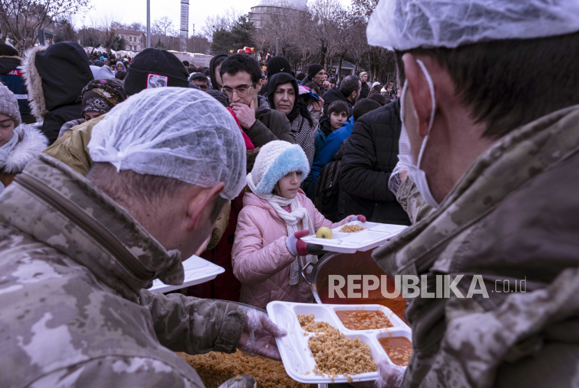 Orang-orang menerima makanan gratis yang dibagikan setelah gempa bumi di Diyarbakir, tenggara Turki, 6/2/2023).
