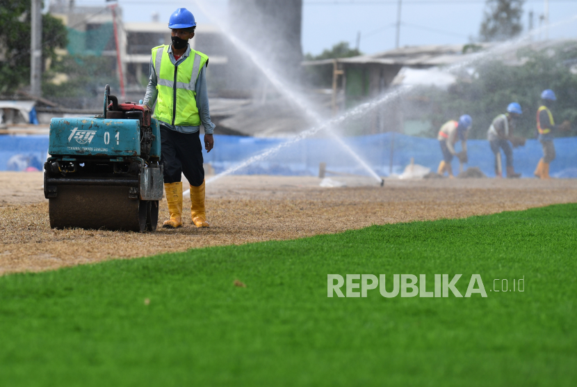 Pekerja menyelesaikan pemasangan rumput lapangan latih di samping Jakarta International Stadium (JIS), Jakarta Utara.