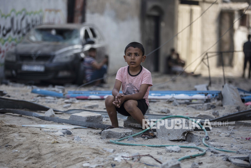 Seorang anak laki-laki Palestina duduk melihat orang lain memeriksa kerusakan toko mereka setelah serangan udara Israel di kamp pengungsi Jabaliya, Jalur Gaza utara, Kamis, 20 Mei 2021. 