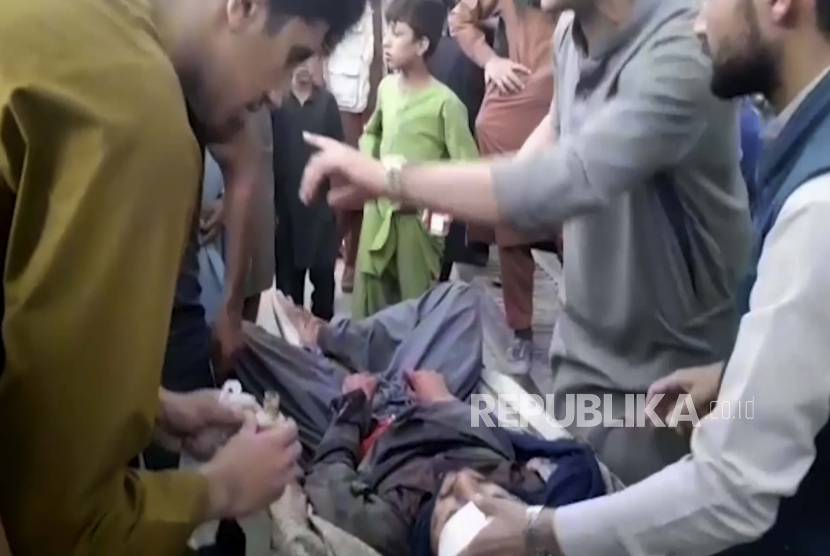Dalam bingkai yang diambil dari video ini, orang-orang merawat seorang pria yang terluka di dekat lokasi ledakan mematikan di luar bandara di Kabul, Afghanistan, Kamis, 26 Agustus 2021.