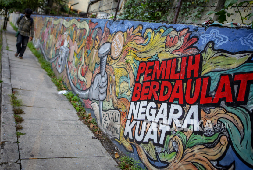 Warga melintas di depan mural bertema pemilihan umum di kawasan Pasar Anyar, Kota Tangerang, Banten, Kamis (7/5/2020). Presiden Joko Widodo menunda pemungutan suara Pemilihan Kepala Daerah (Pilkada) 2020 hingga Desember 2020 akibat wabah COVID-19