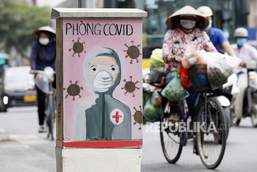 Seorang wanita melewati kotak listrik yang dicat dengan tema COVID-19 di Hanoi, Vietnam, 7 Juni 2021.