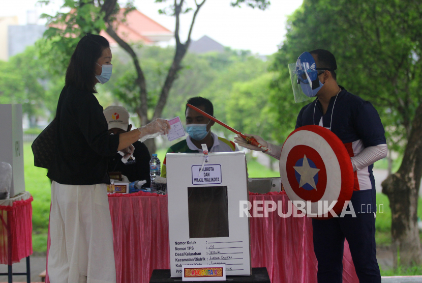 Petugas KPPS berkostum pahlawan super (super hero) berjaga di TPS 14, Perumahan Citraland, Kota Surabaya, Jawa Timur, Rabu (9/12).