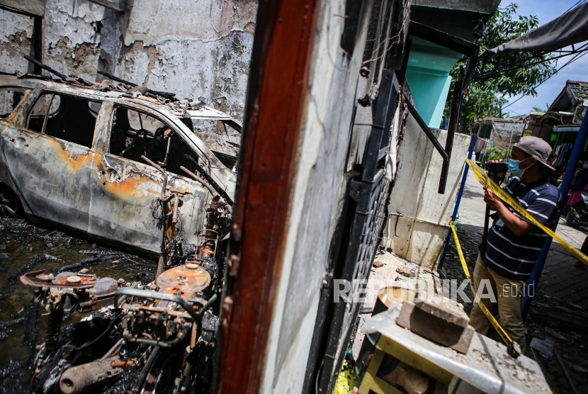 Seorang jurnalis mengambil gambar kondisi rumah yang terbakar di Legok, Kabupaten Tangerang, Banten, Jumat (23/10/2020). Kebakaran yang terjadi pada Jumat (23/10/2020) dini hari tersebut diduga akibat korsleting listrik dan menyebabkan lima anggota keluarga di rumah tersebut meninggal dunia. 