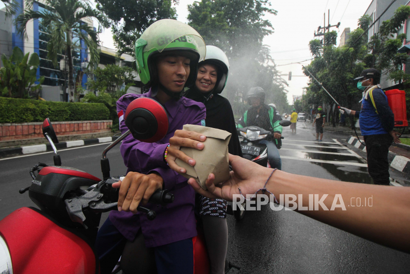 Suporter sepak bola membagikan nasi bungkus kepada pengemudi ojek daring di Jalan Bubutan, Surabaya, Jawa Timur, Jumat (3/4/2020). Sekitar 95 dari 154 kelurahan di Kota Surabaya, Jawa Timur, tercatat nol kasus penularan virus corona jenis baru atau Covid-19. 