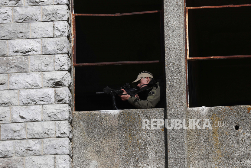 Seorang tentara Israel membidikkan senjatanya selama latihan di sebuah bangunan yang ditinggalkan yang dulunya merupakan markas tentara Suriah 