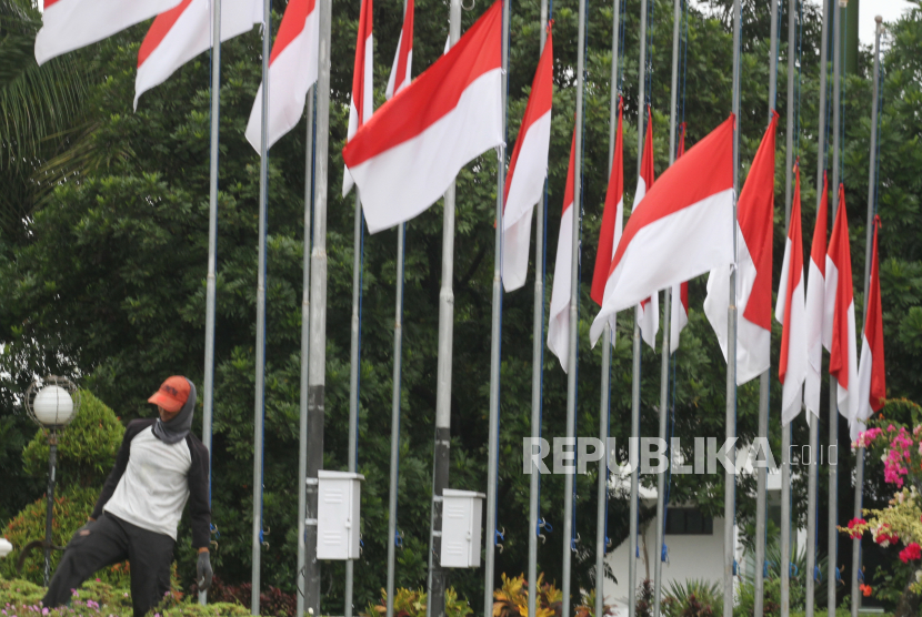 Pekerja melintasi jajaran bendera setengah tiang yang dipajang di lapangan Hellypad Universitas Muhammadiyah Malang, Jawa Timur, Selasa (18/10/2022).