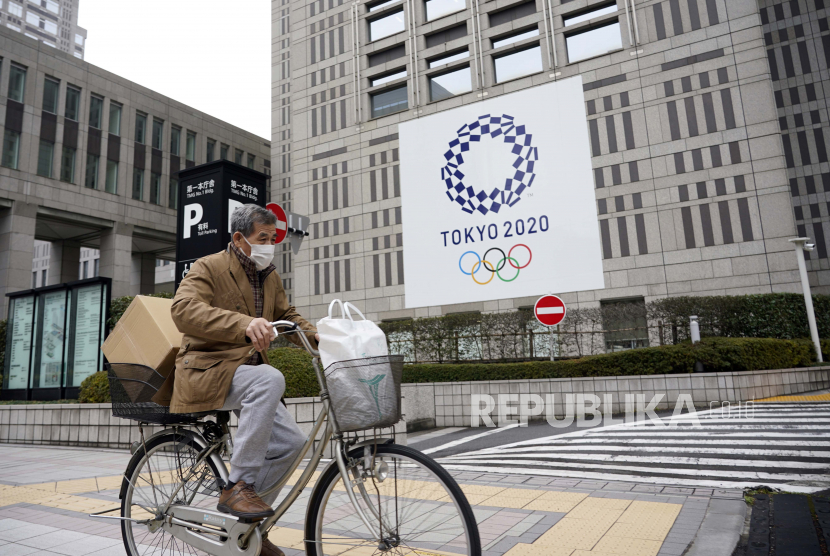 Seorang pria bersepeda melewati papan iklan Olimpiade Tokyo di luar Kantor Pemerintah Metropolitan Tokyo di Tokyo, Jepang, 27 Januari 2021. Konsumsi rumah tangga Jepang pada bulan Februari masih belum menunjukkan pemulihan. 