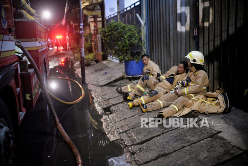  Sejumlah petugas tengah beristirahat sejenak di tengah upaya memadamkan api yang membakar rumah warga imbas kebakaran Depo Pertamina Plumpang di Rawa Badak Selatan, Koja, Jakarta Utara, Jumat (3/3/2023).