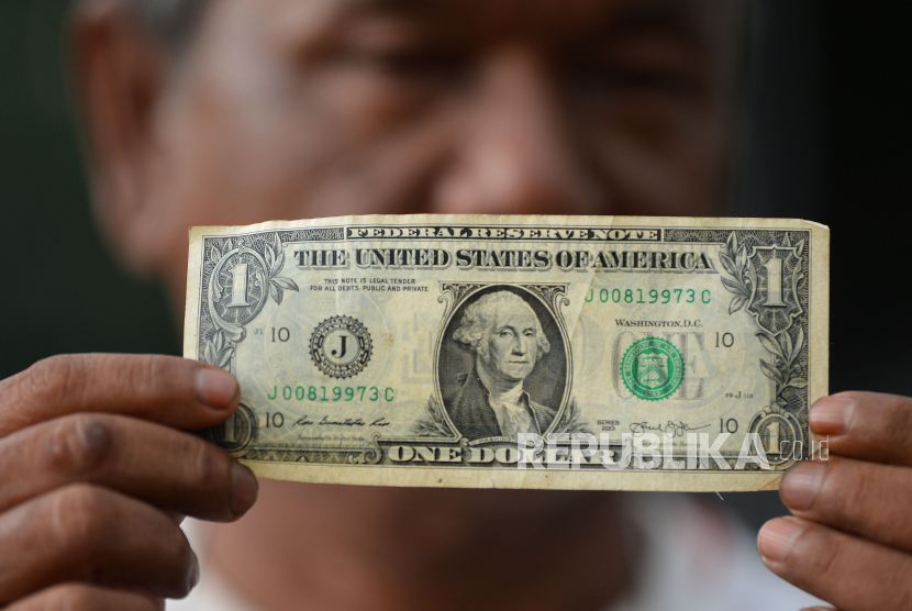 Penyedia jasa penukaran uang menunjukkan selembar uang dolar AS di Kwitang, Jakarta, Senin (23/3/2020). 