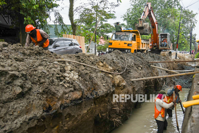 Pekerja dengan menggunakan alat berat memperbaiki drainase di Jalan Sei Belutu, Medan, Sumatera Utara, Kamis (9/12/2021). Pemerintah daerah setempat memperbaiki drainase untuk mengantisipasi genangan saat hujan lebat. 