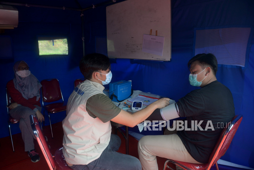 Petugas kesehatan memeriksa kesehatan pemudik dil posko layanan vaksinasi Covid-19 di Rest Area 86 ruas Tol Cipali, Jawa Barat, Selasa (26/4/2022). Satgas meminta cakupan vaksinasi booster di provinsi tujuan mudik bisa ditingkatkan.
