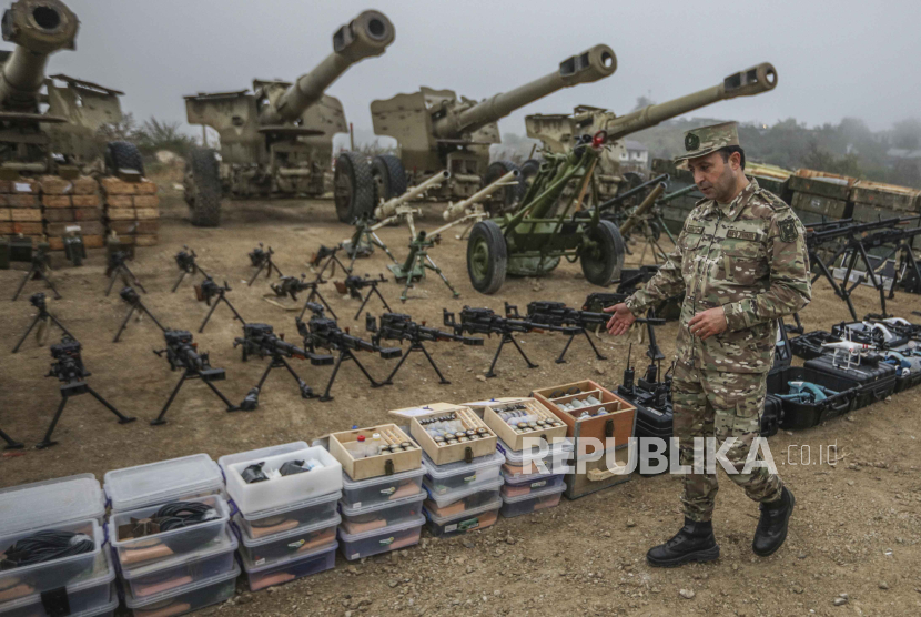 Seorang perwira Angkatan Darat Azerbaijan menunjukkan senjata dan peralatan yang diserahkan oleh pasukan Armenia di Nagorno-Karabakh dipajang di desa Signag, Azerbaijan, Ahad, 1 Oktober 2023.
