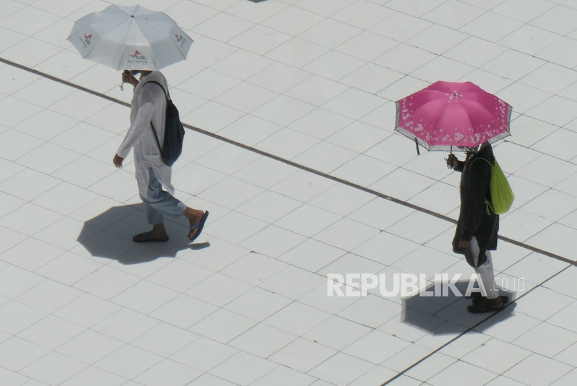 Dua jamaah menggunakan payung usai melaksanakan shalat zuhur di Masjidil Haram, Makkah, Arab Saudi, 