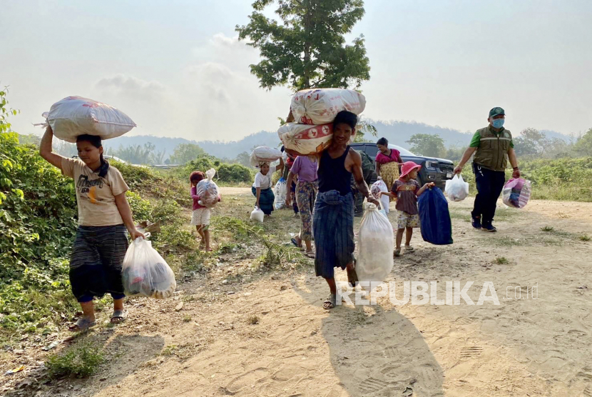 Foto selebaran menunjukkan para pengungsi dari Myanmar membawa barang-barang mereka untuk menyeberangi sungai untuk kembali ke rumah mereka, di kota perbatasan Mae Sot, Thailand .