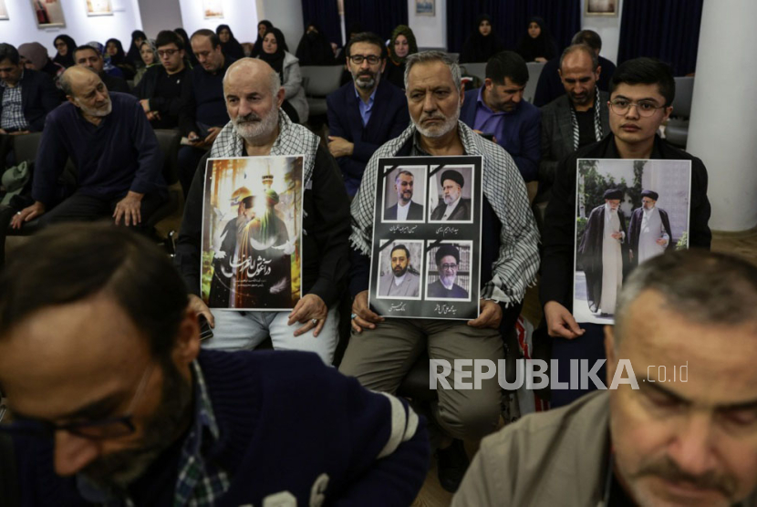 Orang-orang memegang foto mendiang Presiden Iran Ebrahim Raisi dan mendiang Menteri Luar Negeri Iran Hossein Amir Abdollahian saat upacara peringatan korban kecelakaan helikopter di Konsulat Iran di I