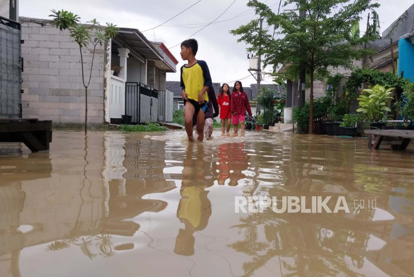 Warga berjalan melewati genangan air banjir di kompleks Suropati Residence, Desa Srimukti, Kecamatan Tambun Utara, Kabupaten Bekasi, Jawa Barat.