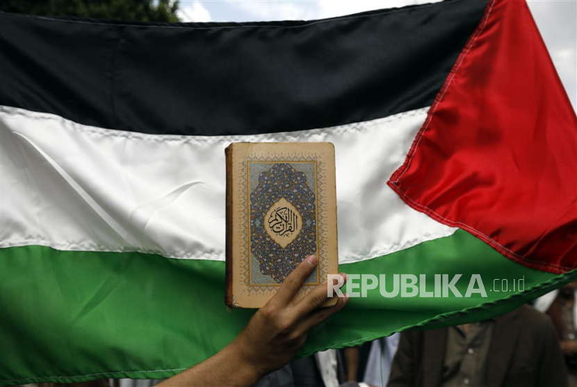 Warga Yaman mengibarkan bendera Palestina dan menunjukan Al quran saat unjuk rasa anti-Israel  di Sanaa, Yaman, (4/7/2023)