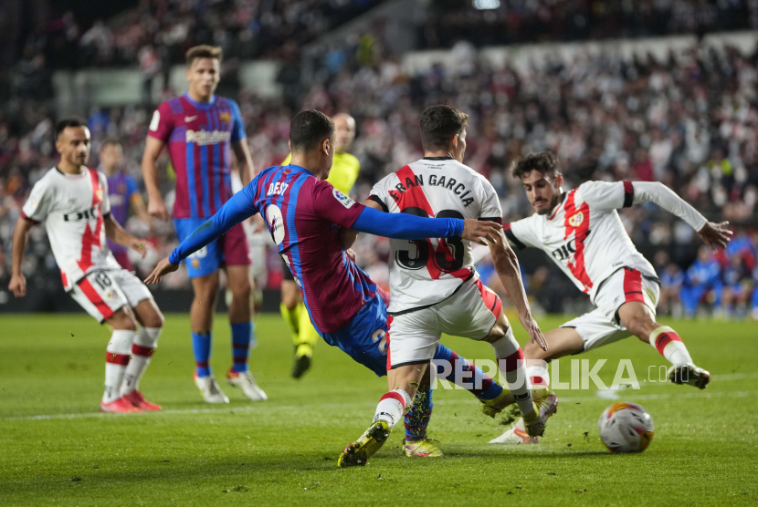  Pemain Barcelona Sergino Dest, kiri, melakukan tembakan ke gawang di depan pemain Rayo Fran Garcia pada pertandingan sepak bola La Liga Spanyol antara Rayo Vallecano dan FC Barcelona di stadion Vallecas di Madrid, Spanyol, Kamis (28/10) dini hari WIB. 