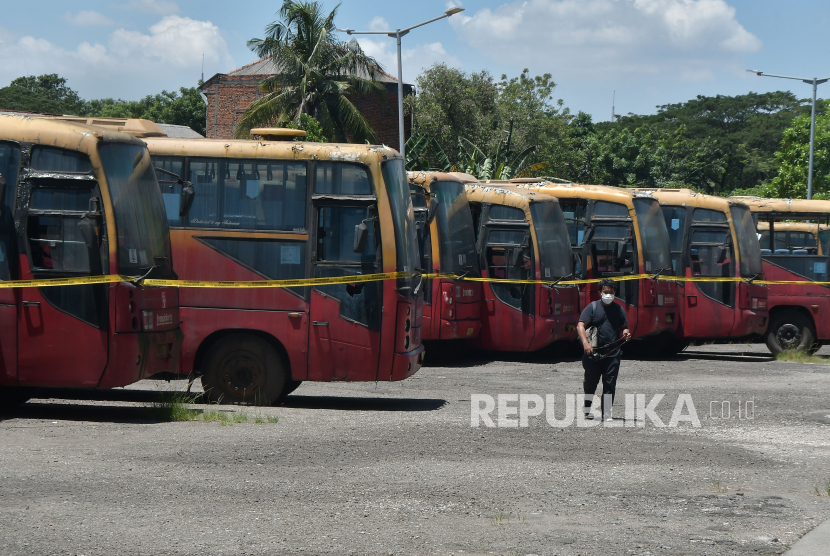 Jurnalis melintas disamping  bus Transjakarta yang parkir di area Terminal Terpadu Pulo Gebang, Jakarta Timur, Rabu (12/4/2023). Dalam rangka menghapus Barang Milik Daerah (BMD), Pemerintah Provinsi DKI Jakarta akan melelang 417 bus Transjakarta yang terbengkalai  
