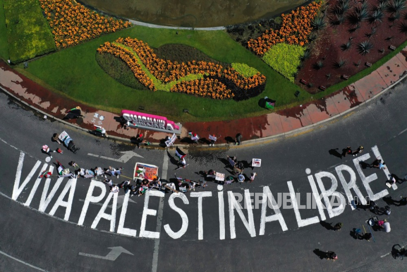 Peserta aksi menulis grafiti Hidup Palestina Merdeka di jalan raya dalam aksi unjuk rasa solidaritas untuk rakyat Palestina .