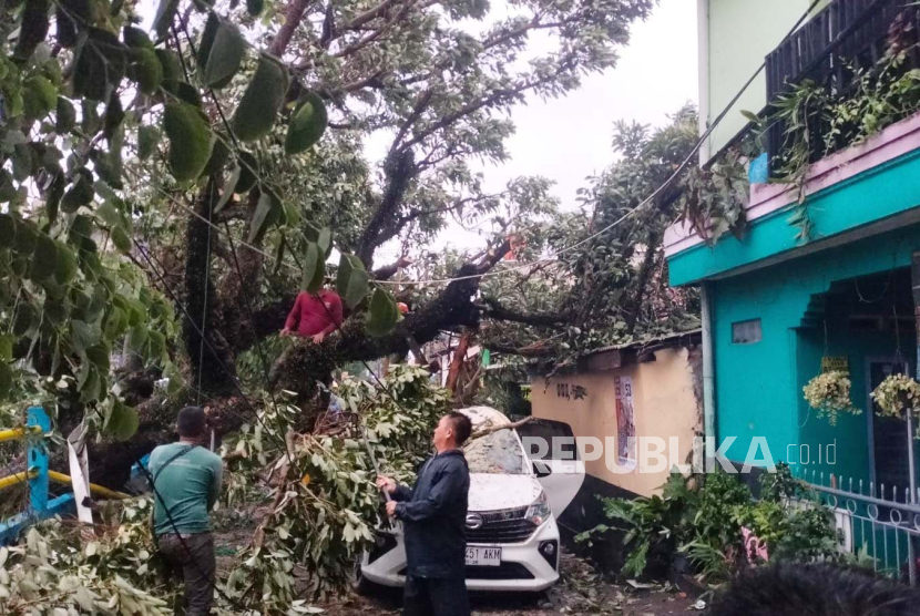 Pohon tumbang menimpa satu mobil yang terparkir di Jalan Pangaritan, Kecamatan Panyileukan, Kota Bandung, Jawa Barat, Senin (11/12/2023). 