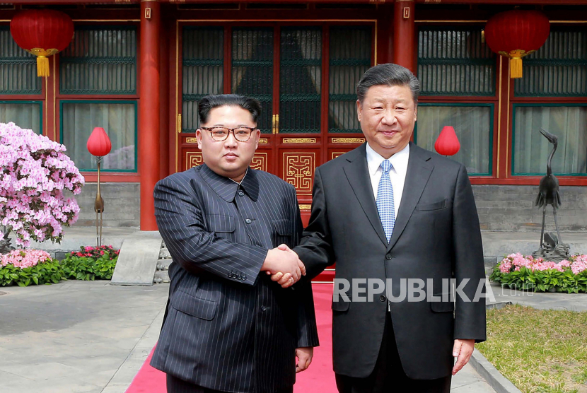  Pemimpin Korea Utara Kim Jong Un, kiri, berjabat tangan dengan Presiden China Xi Jinping di Diaoyutai State Guesthouse di Beijing pada 27 Maret 2018. Konten gambar ini disediakan dan tidak dapat diverifika