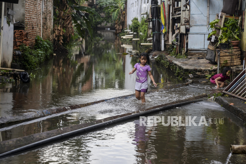 Seorang anak berjalan melewati banjir di sekitar permukiman tempat tinggalnya (ilustrasi) 