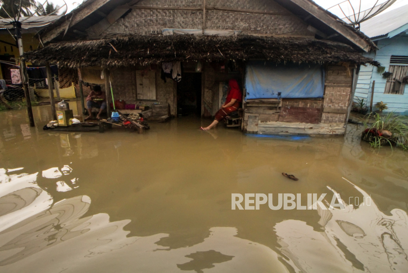 Warga duduk didepan rumah nya yang terendam di Desa Kumbang, Kecamatan Blang Mangat Lhokseumawe, Aceh.