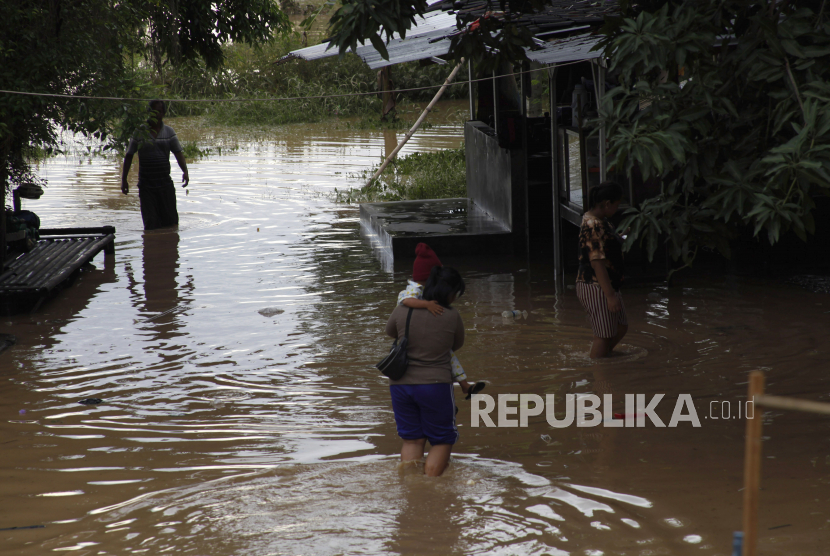 Warga berjalan melintasi banjir yang menggenangi permukiman di Kampung Sewu, Jebres, Solo, Jawa Tengah, Senin (14/12/2020). Puluhan keluarga yang tinggal di sekitar bantaran sungai setempat terdampak luapan air Sungai Bengawan Solo. 