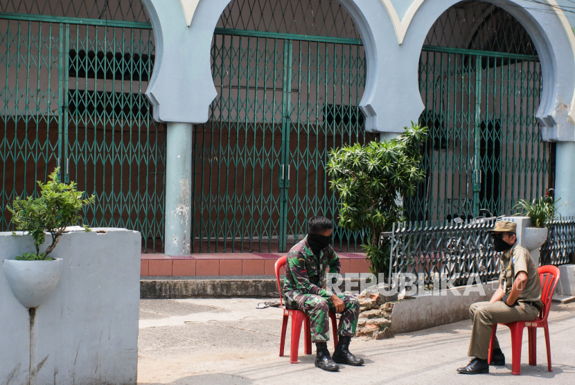 Petugas keamanan berjaga di depan Masjid Jami Kebon Jeruk, Jakarta, Ahad (29/3/2020). Sebanyak 183 jamaah Masjid Jami Kebon Jeruk diisolasi di dalam masjid karena berstatus Orang Dalam Pemantauan (ODP)