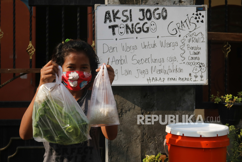 Warga menunjukkan bahan makanan gratis yang diambil dari pagar rumah di kawasan Medayu Utara, Surabaya, Jawa Timur, Selasa (5/5/2020).  Warga kampung Medayu Utara menggelar kegiatan sosial bernama 