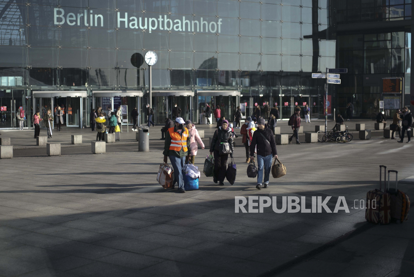  Seorang sukarelawan berbaju merah membantu para pengungsi dari Ukraina setelah mereka tiba di stasiun kereta utama di Berlin, Jerman, Rabu, 16 Maret 2022.  Menteri Dalam Negeri Jerman Nancy Faeser menghadapi tuduhan serius mengenai manipulasi jumlah pengungsi di negaranya.