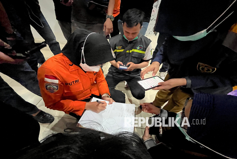 Seorang petugas penyelamat dari Badan Nasional Pencarian dan Pertolongan (Basarnas) mencatat nama-nama korban selamat dari kecelakaan kapal feri di sebuah pelabuhan di Banjarmasin, Kalimantan Selatan, Ahad (13/9/2026).