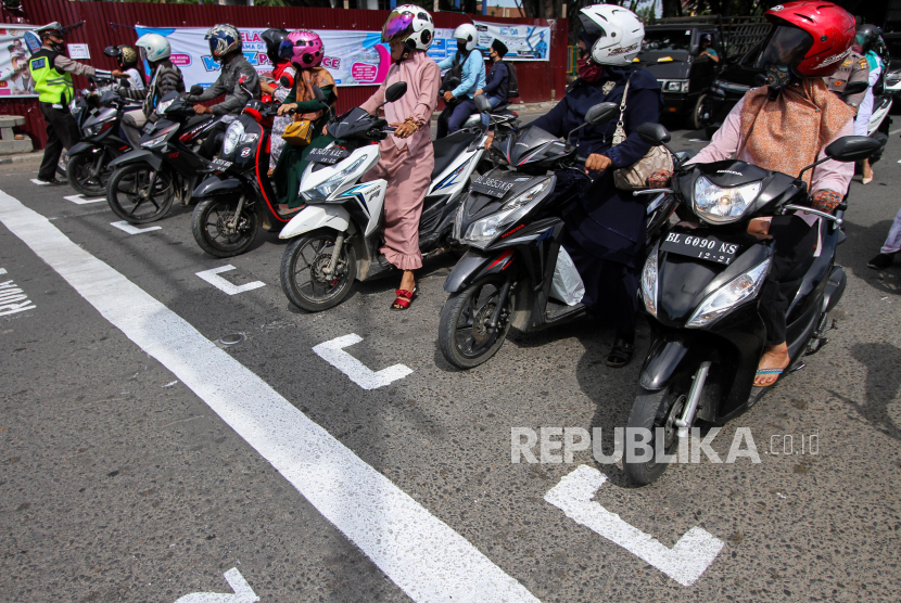 Polisi mengatur pengendara sepeda motor untuk berhenti di belakang garis untuk menjaga jarak antarpengendara saat sosialisasi penerapan jaga jarak di Kota Lhokseumawe, Aceh, Rabu (15/7/2020). 
