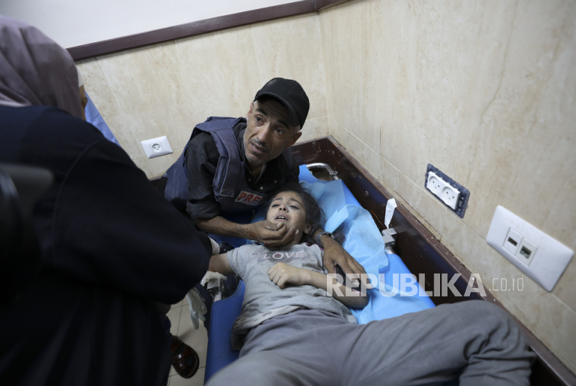 Seorang jurnalis Palestina menenangkan keponakannya yang terluka dalam serangan Israel di rumah keluarganya di kamp pengungsi Nusseirat, di sebuah rumah sakit di Deir el-Balah, Jalur Gaza, Ahad (22/10/2023). Dilansir Reuters, serangan udara Israel ke Gaza sejak 7 Oktober 2023 telah mengakibatkan 4.651 warga Palestina meninggal dunia, 40 persen di antaranya adalah anak-anak.