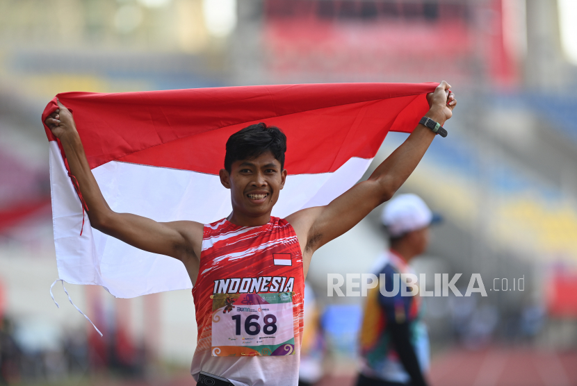 Pelari Indonesia Saptoyogo Purnomo membentangkan bendera usai mencapai garis finis pada final lari 400 meter putra T37 ASEAN Para Games 2022 di Stadion Manahan, Solo, Jawa Tengah, Rabu (3/8/2022). Saptoyogo berhasil meraih medali emas dengan catatan waktu 55,80 detik. 
