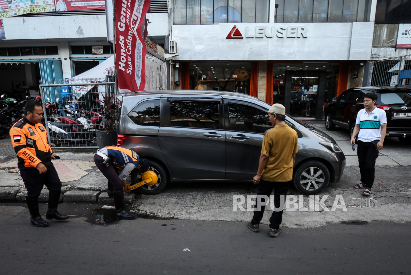 Petugas Dinas Perhubungan (Dishub) Kota Depok memasang gembok pada mobil yang parkir liar di trotoar kawasan Jalan Margonda, Depok, Jawa Barat, Jumat (8/7/2022). 