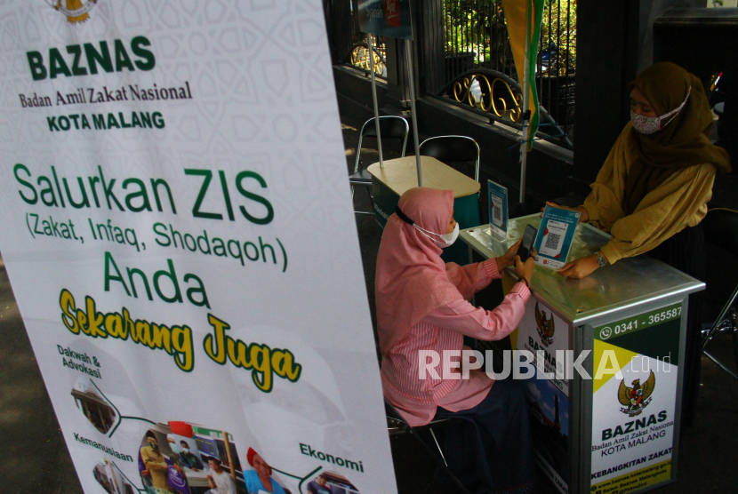 Relawan Badan Amil Zakat Nasional (Baznas) membantu warga membayar zakat fitrah secara daring di tenda zakat. 