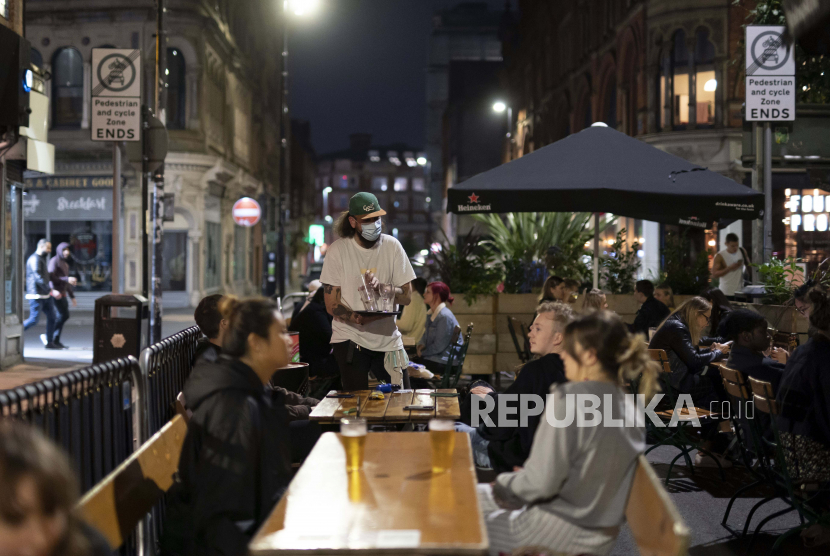 Pegawai Restoran menawarkan makan dan minum di sebuah restoran di Northern Quarter Manchester, Inggris, Selasa (22/9). 