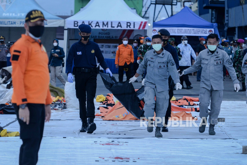 Petugas membawa kantong yang berisi bagian tubuh penumpang Sriwijaya Air.