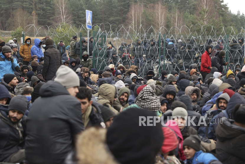 Krisis kemanusiaan di perbatasan Polandia-Belarus masih berlangsung. Ilustrasi Para migran berkumpul di depan pagar kawat berduri dan tentara Polandia di pos pemeriksaan Kuznitsa di perbatasan Belarus-Polandia dekat Grodno, Belarus, pada Senin, 15 November 2021.