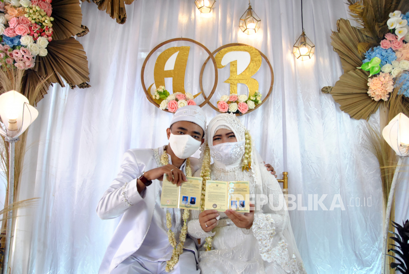 Pasangan pengantin menggunakan masker dan menunjukkan buku nikah (ilustrasi). Pemerintah Kabupaten Rejang Lebong, Provinsi Bengkulu saat ini tengah menyosialisasikan protokol kesehatan pada pelaksanaan acara pernikahan. 