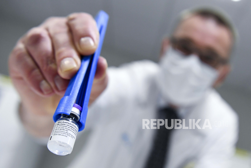 Imam Inggris Serukan Umat Lakukan Vaksinasi. Seorang petugas kesehatan memegang botol vaksin Pfizer-BioNTech COVID-19 saat dicairkan di laboratorium rumah sakit UZ Leuven di Leuven, Belgia, Minggu, 27 Desember 2020. 
