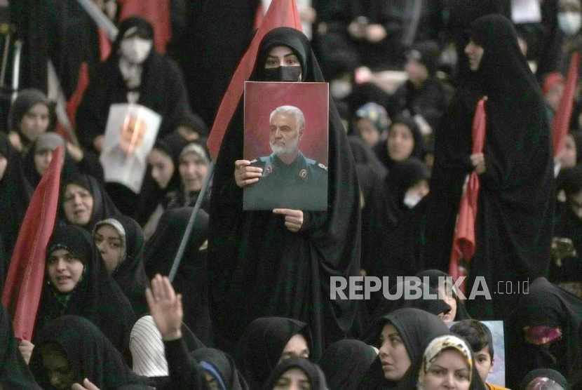 Seorang wanita memegang poster mendiang Jenderal Garda Revolusi Qassem Soleimani, yang terbunuh dalam serangan pesawat tak berawak AS pada 2020 di Irak. 
