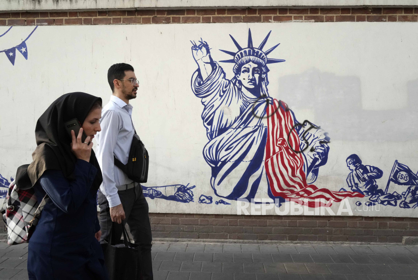 Warga melewati muran anti-AS di dinding bekas Kedubes AS di Teheran, Iran pada 19 Agustus 2023. 