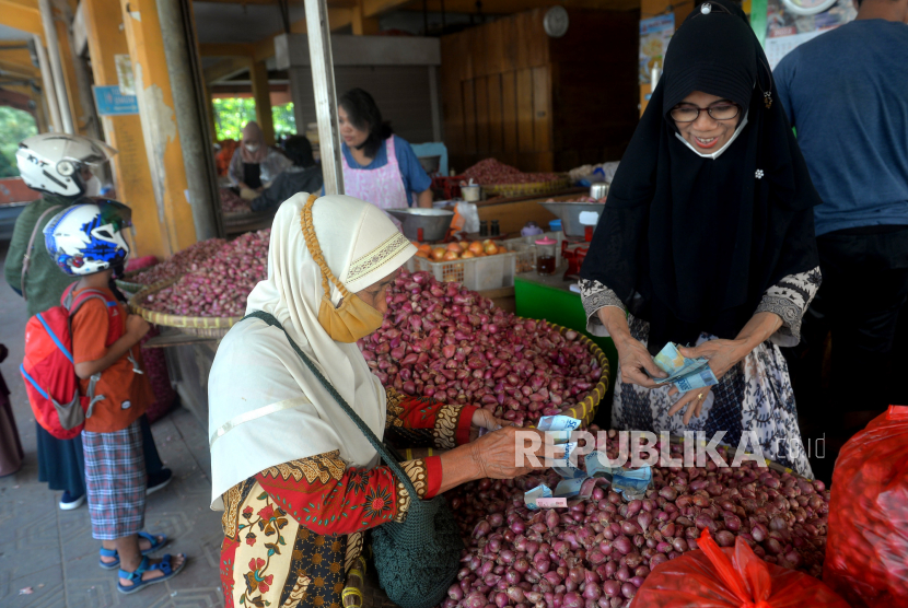 Pedagang bawang merah melayani pembeli di pasar tradisional. 