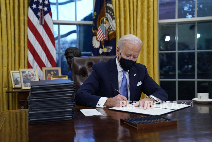  Presiden Joe Biden menandatangani perintah eksekutif pertamanya di Kantor Oval Gedung Putih pada Rabu (20/1/2021), di Washington.
