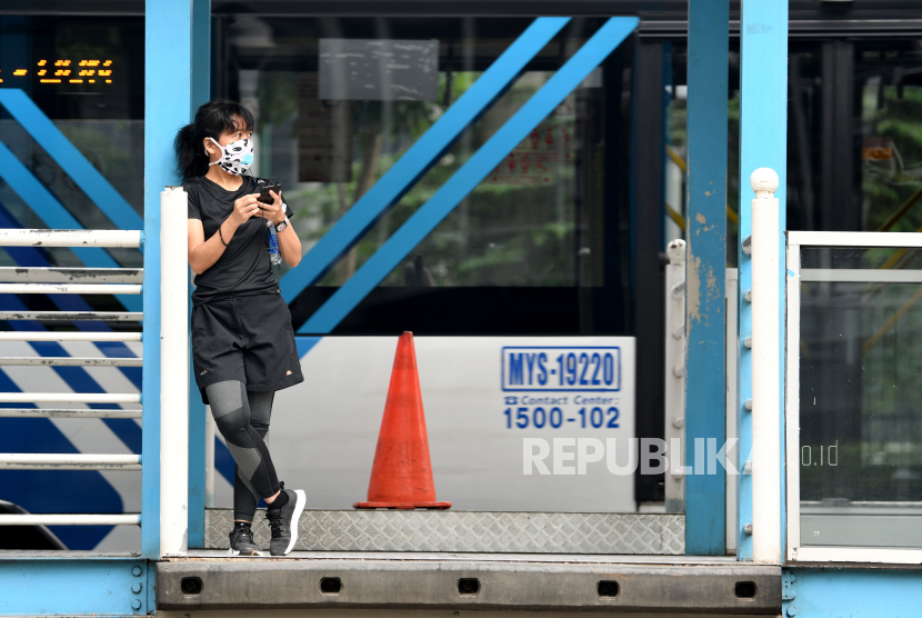 Calon penumpang mengenakan masker menunggu bus TransJakarta di Halte Bundaran Senayan, Jakarta, Ahad (29/3). (ilustrasi)